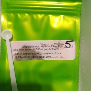 May include: A bright green sealed pouch with a white label and a small white spoon. The label reads "Weeping Willow Gibberellic Acid water soluble 40%" and other text. The pouch contains 5g of powder.