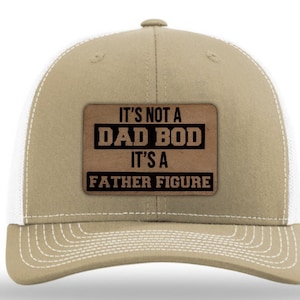 May include: A tan and white trucker hat with a brown patch that reads "It's not a Dad Bod It's a Father Figure".
