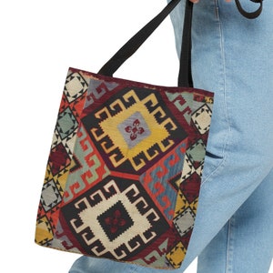 May include: A tote bag with a colorful geometric pattern inspired by traditional rugs. The bag has black straps and a large, rectangular shape.