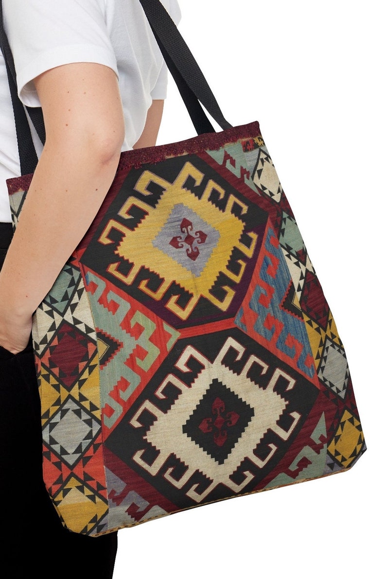 May include: A large tote bag with a colorful geometric pattern. The pattern is reminiscent of a traditional rug or tapestry. The bag has black straps.