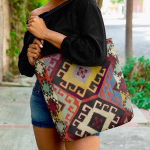 May include: A large tote bag with a colorful geometric pattern. The bag is made of a woven fabric and has a black background with red, blue, yellow, and green accents.