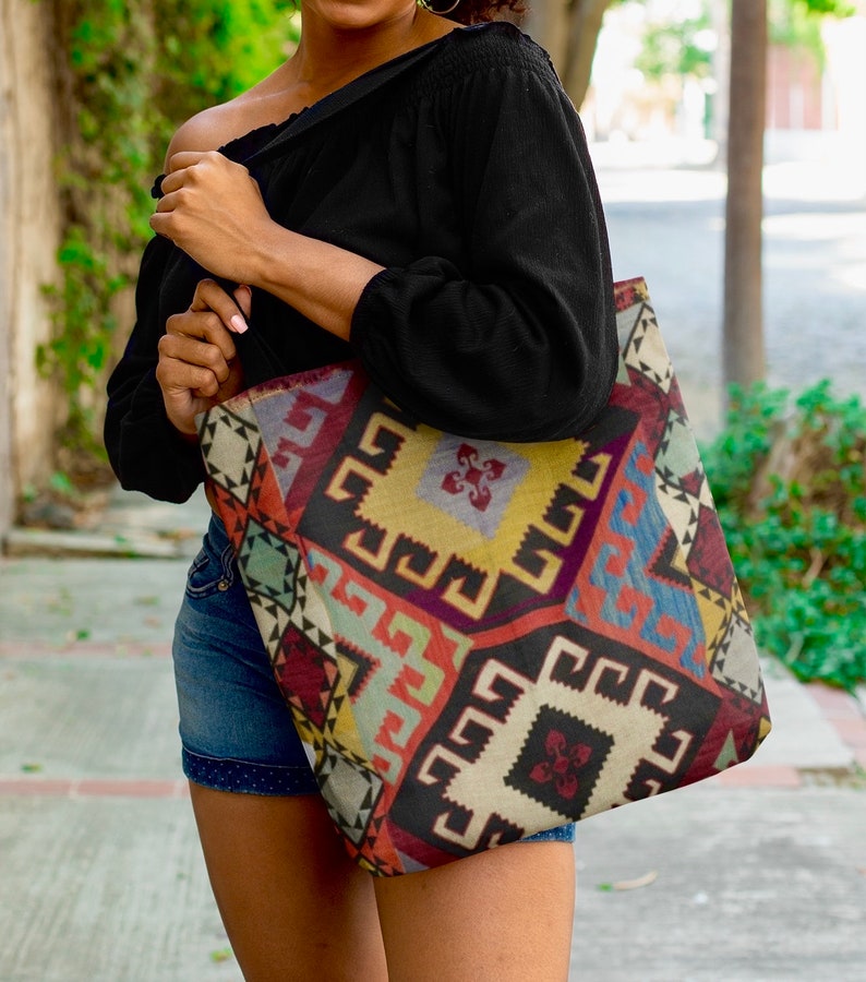 May include: A large tote bag with a colorful geometric pattern. The bag is made of a woven fabric and has a black background with red, blue, yellow, and green accents.