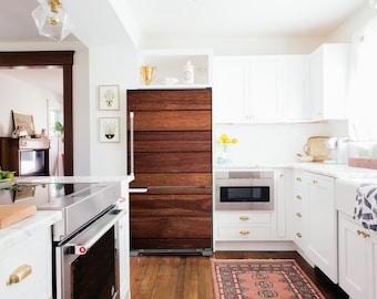 May include: A white kitchen with a wood-paneled refrigerator, white cabinets, and a stainless steel oven and microwave. The kitchen has a marble countertop and a white farmhouse sink.