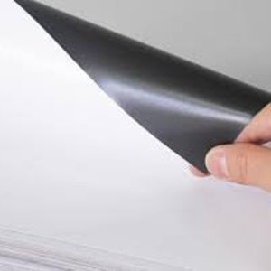 Pode incluir: Uma pilha de papel branco com um suporte magn&eacute;tico preto. O papel &eacute; projetado para impress&atilde;o e pode ser usado para artesanato, projetos e outras atividades criativas.