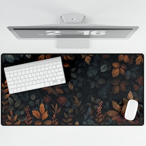 Può includere: Un tappetino per mouse con un design floreale nero e marrone con una tastiera bianca e un mouse bianco sopra.