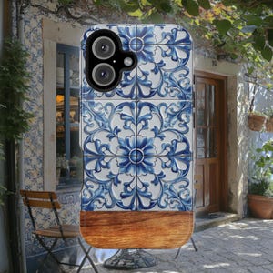 Puede incluir: Funda de teléfono inteligente con un diseño de azulejos florales azules y blancos en la parte superior y un patrón de vetas de madera en la parte inferior. La funda tiene un recorte para la cámara y está diseñada para proteger el teléfono.