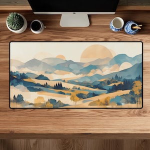 May include: A rectangular desk mat featuring a landscape illustration of rolling hills, mountains, and trees in a colour palette of muted blues, soft yellows, and warm beige tones, with large circular shapes representing the sun or moon.