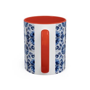 May include: White ceramic mug with a blue floral tile pattern. The interior and handle are bright orange. The mug features a classic design, perfect for coffee, tea, or any favourite beverage.
