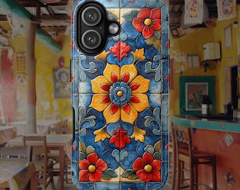 Op de afbeelding: Een smartphonehoesje met een kleurrijk tegelpatroon met een centraal geel en blauw bloemmotief, omringd door rode bloemen en ingewikkeld blauw krulwerk, alles geplaatst op een raster van gebarsten, verweerd uitziende tegels.