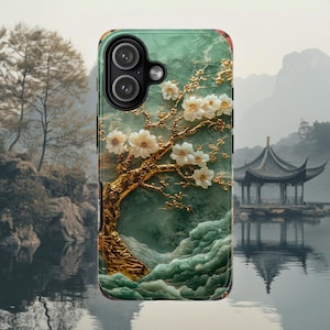 May include: A rectangular smartphone case featuring a green marble-like background with a textured gold tree trunk and white floral blossoms. The design includes a prominent camera cutout in the upper left corner with two circular lenses.