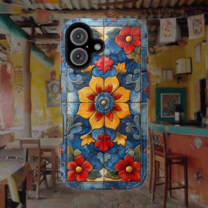 May include: A phone case with a colourful floral design. The case features a blue background with yellow, red and white flowers. The case has a camera cutout and a raised lip around the edges.