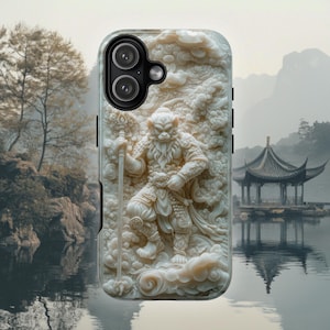 May include: A phone case featuring a detailed, cream-coloured relief carving of a monkey warrior holding a staff. The figure is surrounded by swirling cloud motifs and intricate patterns, set against a background of a traditional pavilion by water.