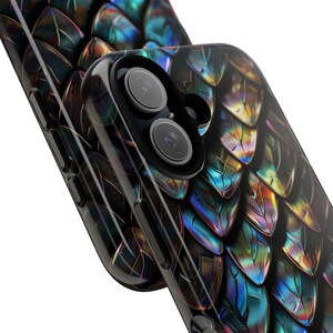 May include: A smartphone case featuring a glossy, iridescent dragon scale pattern in shades of deep blue, purple, and gold. The case has a black camera cutout frame with two circular lenses visible, and black side buttons along the edge.