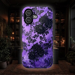 May include: A smartphone case featuring a vibrant purple background with a detailed black floral lace pattern. The design includes multiple rose motifs and intricate vine details, with a dual-camera cutout located in the upper left corner.