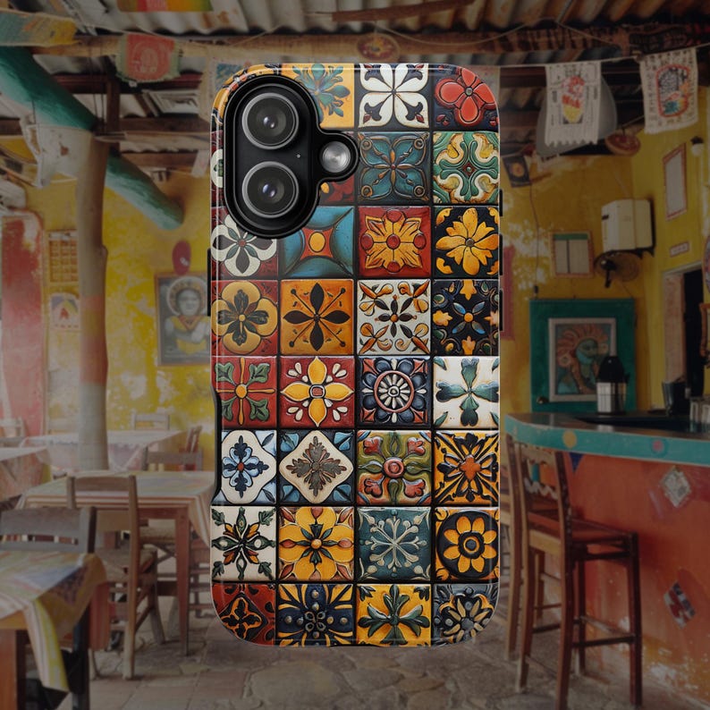 Op de afbeelding: Een rechthoekig smartphonehoesje met een rasterpatroon van kleurrijke vierkante tegels. Elke tegel toont een uniek bloemmotief of geometrisch patroon in tinten geel, rood, blauw, groen en wit. Het hoesje heeft een zwarte camera-uitsparing.