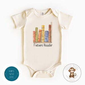 May include: A cream colored baby onesie with a watercolor illustration of a bookshelf with colorful books. The text "Future Reader" is printed below the bookshelf.