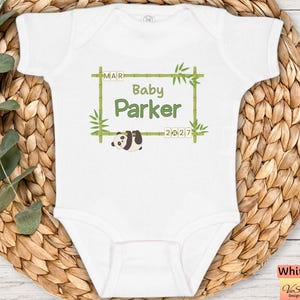May include: White baby onesie with the text "Baby Parker" inside a bamboo frame, a panda bear illustration, and the date 2027. The onesie is on a woven wicker background.