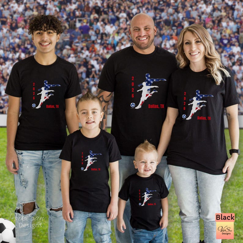 May include: Black t-shirts with a soccer-themed graphic featuring a player silhouette in red, white, and blue, the text "2026 Dallas, TX", and a soccer ball. The shirts are worn by a family of five.