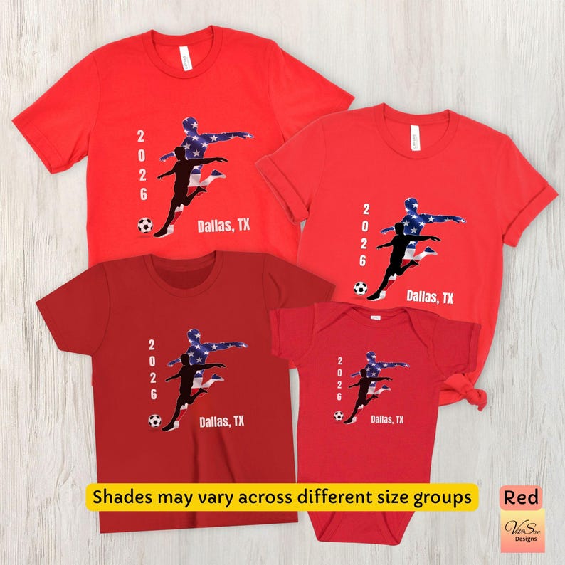 May include: Red t-shirts and a onesie with a soccer player graphic in blue, white, and black. The text "2026 Dallas, TX" is printed on each shirt. The image also includes the text "Shades may vary across different size groups" and "Red".