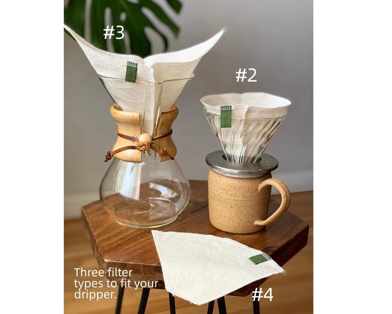 May include: A glass coffee carafe with a wooden collar and leather tie, a ceramic mug with a metal dripper, and three off-white fabric coffee filters with green tabs labeled #2, #3, and #4. The text reads: Three filter types to fit your dripper.