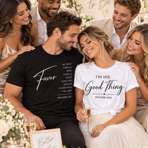 May include: A black t-shirt with white text reading Favor, He who finds a wife finds a good thing and obtains favor from the Lord, Proverbs 18:22, and a white t-shirt with black text reading I'm His Good Thing, Proverbs 18:22 with a small heart.