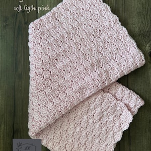 Puede incluir: Una manta de ganchillo rosa claro con un borde festoneado. La manta est&aacute; doblada, mostrando el intrincado patr&oacute;n de puntadas. El texto en la imagen dice "Baby Pink Color, soft light pink."
