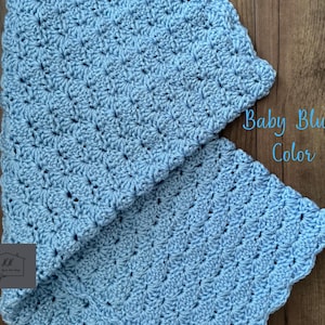 Puede incluir: Una manta de ganchillo azul beb&eacute; con un patr&oacute;n texturizado. La manta est&aacute; doblada, revelando su intrincado trabajo de puntadas y bordes festoneados. El texto en la imagen dice "Baby Blue Color".