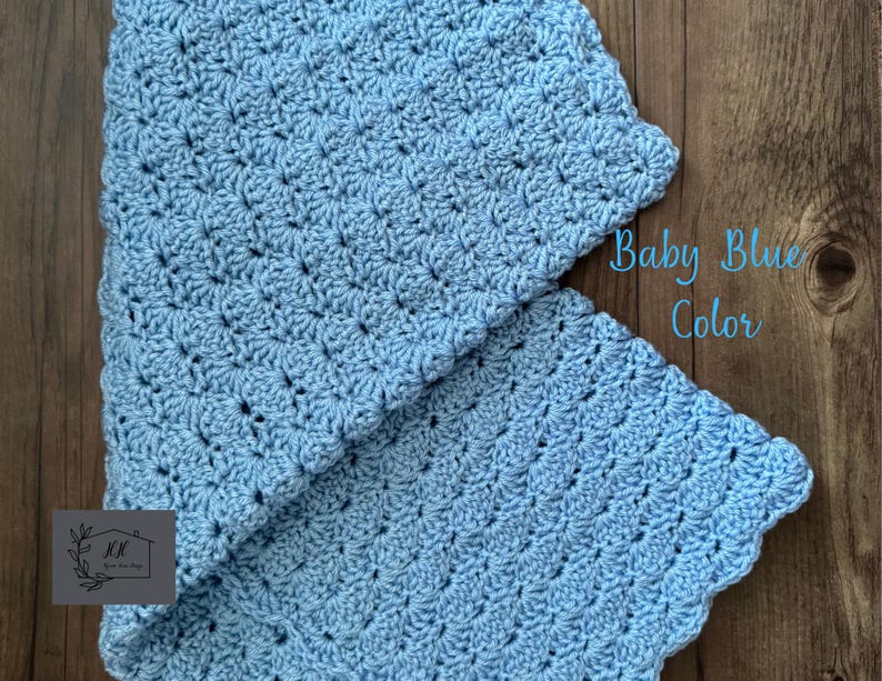 Puede incluir: Una manta de ganchillo azul beb&eacute; con un patr&oacute;n texturizado. La manta est&aacute; doblada, revelando su intrincado trabajo de puntadas y bordes festoneados. El texto en la imagen dice "Baby Blue Color".