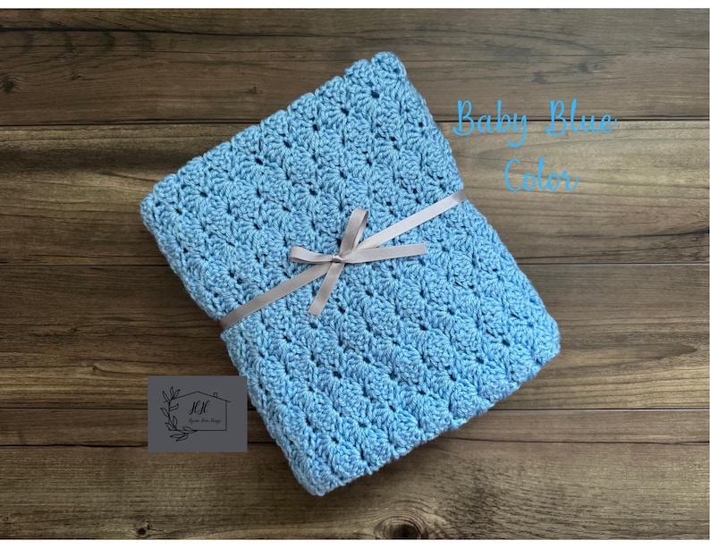 Puede incluir: Una manta de ganchillo azul beb&eacute; atada con una cinta gris. La manta est&aacute; doblada y tiene un patr&oacute;n texturizado. El texto en la imagen dice "Baby Blue Color".