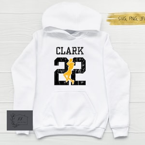 May include: White hoodie with black text that says "CLARK 22" and a yellow silhouette of a basketball player.