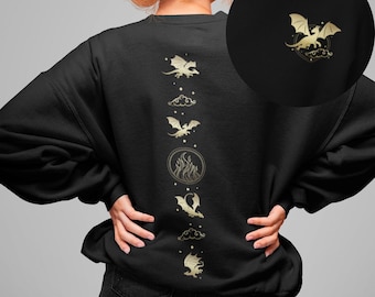 Puede incluir: Sudadera negra con un diseño dorado de dragones y nubes en la espalda. El diseño es vertical y presenta cinco dragones en diferentes poses.
