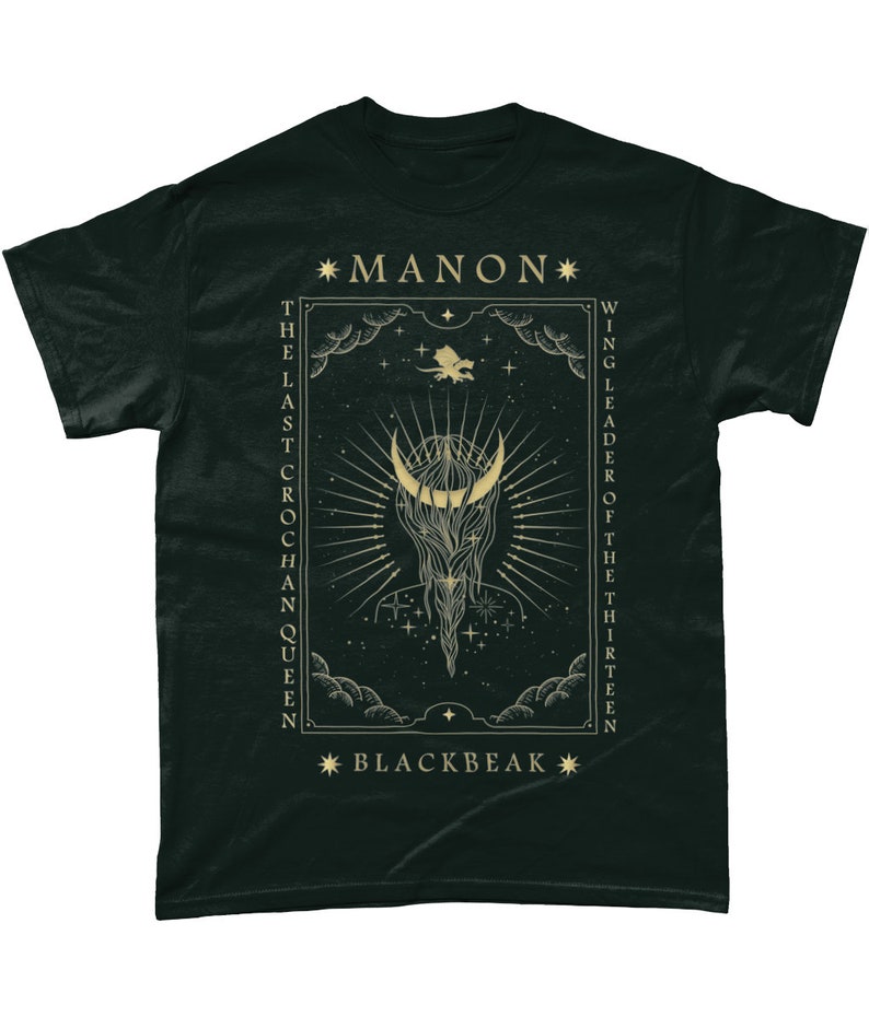 May include: Black t-shirt with a gold graphic design featuring a crescent moon, stars, and the text "*MANON* THE LAST CROCHAN QUEEN WING LEADER OF THE THIRTEEN *BLACKBEAK*"