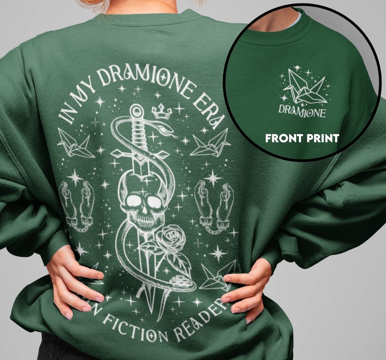 K&ouml;nnte beinhalten: Gr&uuml;nes Sweatshirt mit einem wei&szlig;en Grafikdruck eines Sch&auml;dels, Schwerts, einer Schlange und Sternen. Der Text "In My Dramione Era" und "Fiction Reader" ist auf dem Sweatshirt aufgedruckt. Die Vorderseite des Sweatshirts hat eine wei&szlig;e Origami-Kranichgrafik mit dem aufgedruckten Text "Dramione".