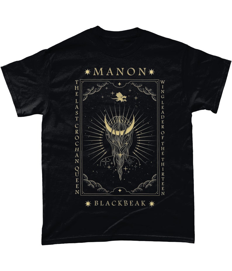 May include: Black t-shirt with a gold graphic design featuring a crescent moon, stars, and the text "*MANON* THE LAST CROCHAN QUEEN WING LEADER OF THE THIRTEEN *BLACKBEAK*"