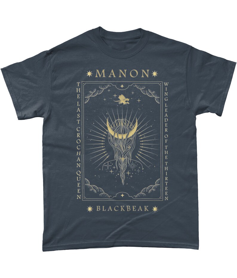May include: A dark blue t-shirt with a gold graphic design featuring a crescent moon, stars, and the text "*MANON* THE LAST CROCHAN QUEEN WING LEADER OF THE THIRTEEN *BLACKBEAK*"