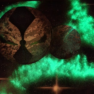 Op de afbeelding: Een abstract schilderij in zwart en groen met een glow-in-the-dark-effect. Het schilderij toont twee grote cirkels met een kleinere cirkel in het midden. De cirkels worden omringd door een groene gloed.