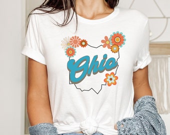 May include: White t-shirt with a blue and brown graphic of the state of Ohio with the word "Ohio" in blue and surrounded by colorful flowers.