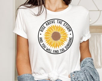 May include: White t-shirt with a yellow sunflower graphic and the text "Rise above the storm and you will find the sunshine."