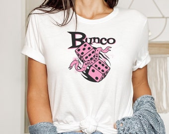 May include: White t-shirt with a pink and black dice graphic and the text "Bunco Roll Baby".