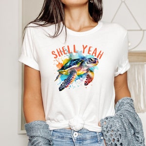 May include: White t-shirt featuring a watercolour illustration of a sea turtle and the text "Shell Yeah" in orange.