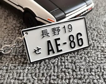 May include: White metal keychain with a black and white license plate that says "長野 19  AE-86".
