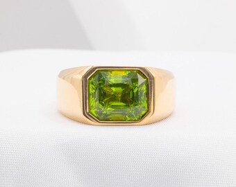 May include: A gold ring featuring a large, green gemstone set in a square shape.