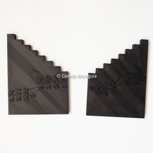May include: Two black plastic rulers with angled edges and numbered markings. The rulers are designed for measuring angles and slopes.