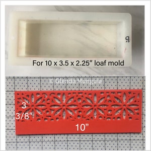 May include: A clear rectangular loaf mold with the text "For 10 x 3.5 x 2.25" loaf mold" above a red decorative piece. The red piece is 10 inches long and 3 3/8 inches wide, with a floral pattern.