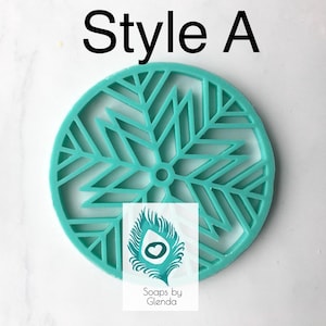 Op de afbeelding: Een ronde siliconen mal in tealblauw met een sneeuwvlokkenpatroon. De mal is geschikt voor het maken van zeep of andere knutselprojecten. De tekst "Soaps by Glenda" is zichtbaar in de afbeelding.