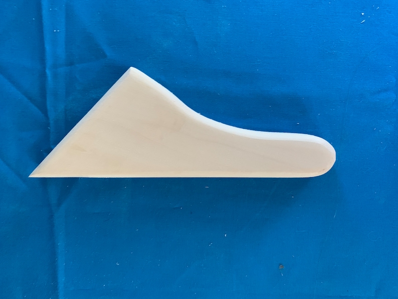 May include: White plastic scraper tool with a curved edge. The tool is designed for spreading and smoothing materials.