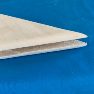 May include: A white wooden fin with a slightly curved shape. The fin is made of two pieces of wood that are joined together.