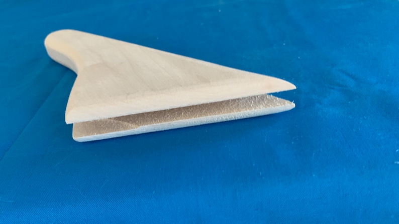 May include: A white wooden fin with a slightly curved shape. The fin is made of two pieces of wood that are joined together.