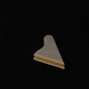 May include: A wooden corner brace with a light brown color. The brace is made of two pieces of wood that are joined together at a 90-degree angle.