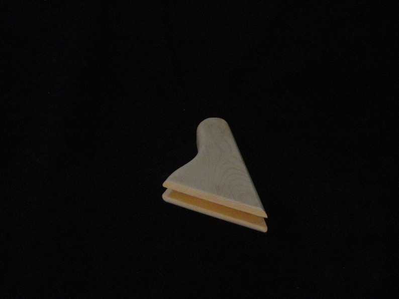 May include: A wooden corner brace with a light brown color. The brace is made of two pieces of wood that are joined together at a 90-degree angle.